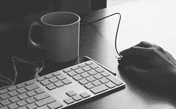 Computer keyboard, a hand guiding a mouse, and a cup of coffee
